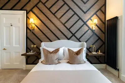 a bedroom with a white bed with a wooden wall at The Devonshire Suite - Your 5 STAR West End Stay! in Glasgow
