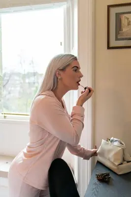 a woman brushing her teeth in front of a window at The Devonshire Suite - Your 5 STAR West End Stay! in Glasgow