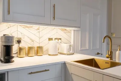 a kitchen with white cabinets and a counter top with a sink at The Devonshire Suite - Your 5 STAR West End Stay! in Glasgow