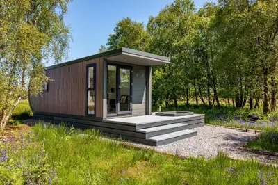 a small cabin in a field with trees at The Stag, Luxury pod with hot tub, Croft4glamping in Oban