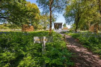 a sign in the middle of a garden with bluebonnets at The Stag, Luxury pod with hot tub, Croft4glamping in Oban