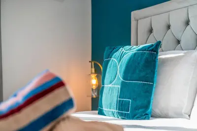 a bed with blue and white pillows on it at Quirky, Family Home in Glasgow in Cardonald