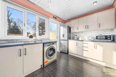 a kitchen with white cabinets and a washer and dryer at Quirky, Family Home in Glasgow in Cardonald