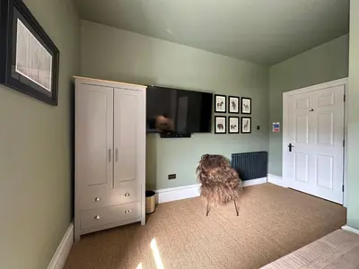 a room with two white cabinets and a dog sitting in the corner at Rooms Above Sugar Boat in Helensburgh