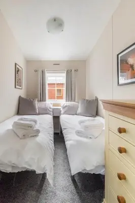two beds in a room with a desk and a window at Poppy Lodge Glendevon Scotland in Glendevon