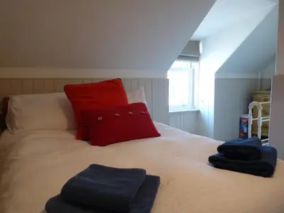 a bed with a red pillow and blue towels on it at The Bothy, Gallin, Glenlyon, Perthshire in Bridge of Balgie