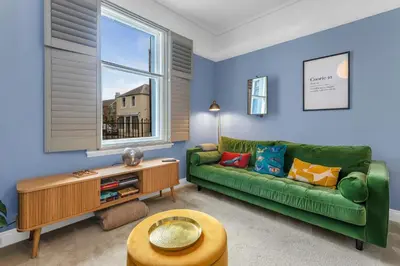 a living room with a green couch and a window at Beeswing, a Victorian Gem in Biggar in Biggar
