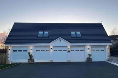 a garage with white doors and a black roof at Little Gleddoch in Dumbarton