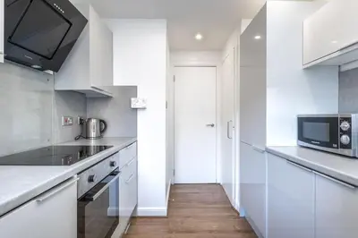 a kitchen with white cabinets and a microwave at ** Modern Merchant City 1 BED Apartment with Free Parking ** in Glasgow