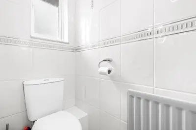 a white bathroom with a toilet and a window at I'm Your Host - Bridgeton House in Glasgow