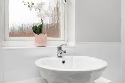 a bathroom with a sink and a window with a flower vase at I'm Your Host - Bridgeton House in Glasgow