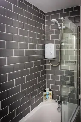 a bathroom with a shower and a bath tub at Modern bright studio apartment in south Glasgow in Glasgow