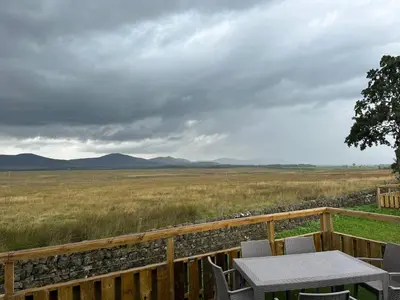a table and chairs on a deck with a view of a field at Green Law - Dog Friendly in Penicuik