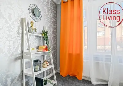 an orange curtain next to a white shelf next to a window at Coats Street Apartment by Klass Living Coatbridge in Coatbridge