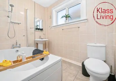 a bathroom with a tub and a toilet and a sink at Coats Street Apartment by Klass Living Coatbridge in Coatbridge