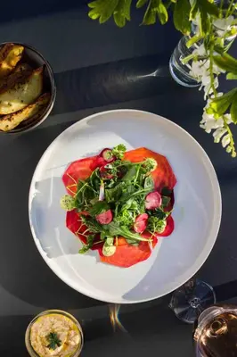 a plate of food with a salad on a table at Sleeps 10. The Old pink library by loch and river in Lochearnhead