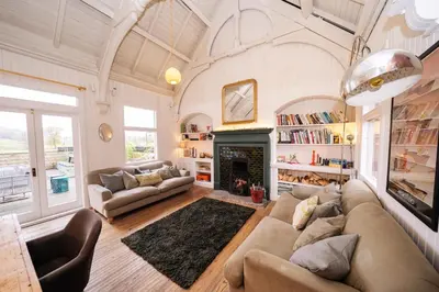 a living room with a couch and a fireplace at Sleeps 10. The Old pink library by loch and river in Lochearnhead