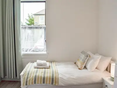 a small bedroom with a bed with a window at Miners Cottage in Girvan