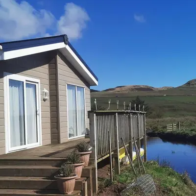 a house with a wooden porch and a fence at Homeston Lodge in Drumlemble