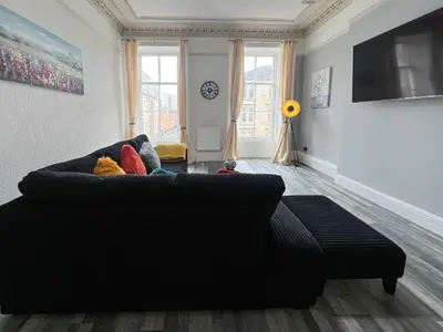 a living room with a black couch and some windows at Premium 2BR Flat in the City Centre in Glasgow