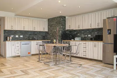a kitchen with white cabinets and a table and chairs at Lavish 2 bed sleeps 5 near Lanark in Carstairs