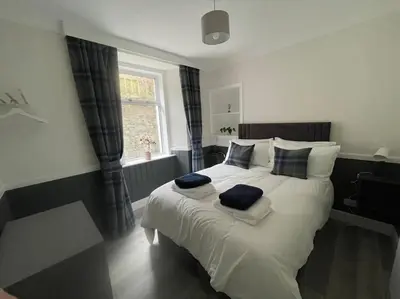 a bedroom with a large bed with two pillows on it at Strathisla Garden Apartment, Oban in Oban