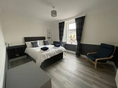 a hotel room with a bed and a chair at Strathisla Garden Apartment, Oban in Oban