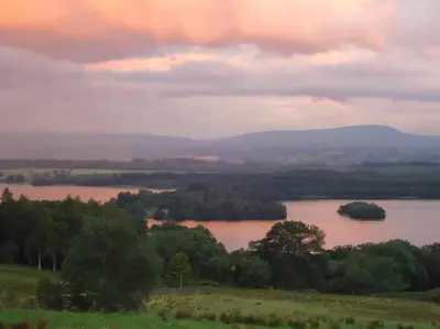 a view of a river with trees in a field at The Mews - a cottage with a spectacular lake view in Port of Menteith