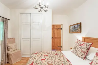 a bedroom with a bed and a chair in it at The Mews - a cottage with a spectacular lake view in Port of Menteith
