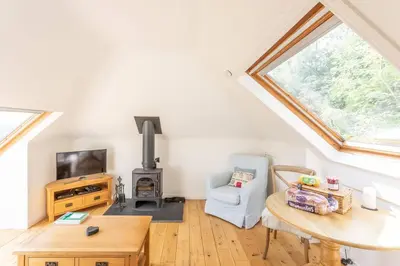 a living room with a table and a wood stove at The Mews - a cottage with a spectacular lake view in Port of Menteith