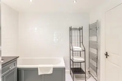 a white bathroom with a tub and a towel ladder at The Stable - cottage with a spectacular lake view in Port of Menteith