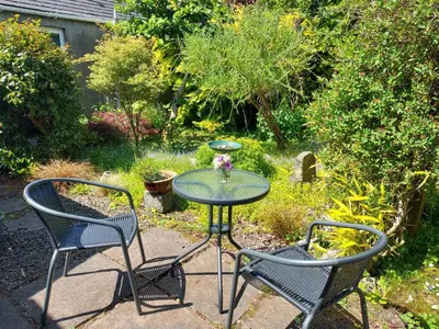 a glass table with two chairs and a vase of flowers at BARHOLM CROFT Holiday Cottage in Creetown