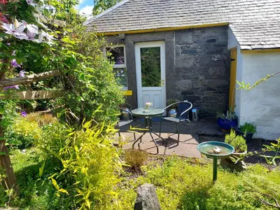 a patio with a table and chairs in a garden at BARHOLM CROFT Holiday Cottage in Creetown