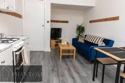 a kitchen and a living room with a blue couch at Complex Suite in Glasgow
