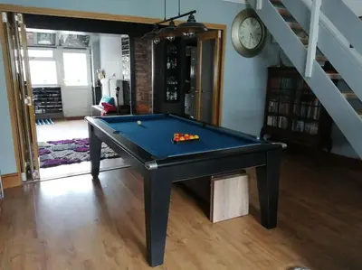 a pool table in a living room with a clock at Aigas Cottage in Glasgow