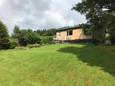 a house in a yard with a large grass field at Glengarry Lodge in Tyndrum