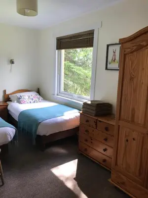 a bedroom with a bed and a window and a dresser at Glengarry Lodge in Tyndrum