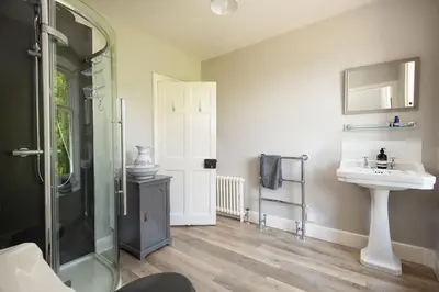 a bathroom with a glass shower and a sink at Mossfennan House in Drummelzier