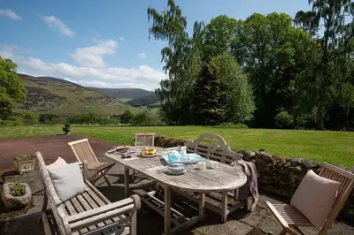 a wooden table and chairs on a patio at Mossfennan House & Annexe in Drummelzier