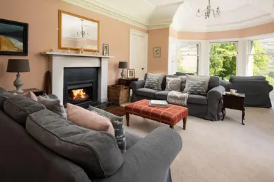 a living room with couches and a fire place at Mossfennan House & Annexe in Drummelzier
