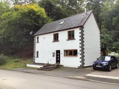 a white house with a car parked in front of it at Eakie House Apartments - Kinlochleven in Kinlochleven
