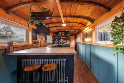 a kitchen with blue cabinets and a bar with wooden stools at The Carriage at Creagan in Creagan