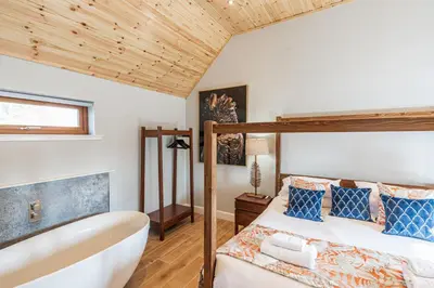 a bedroom with a bed and a bathtub and a bed and a bathtub at Kestrel Lodge 2 with Hot Tub in Newton Stewart