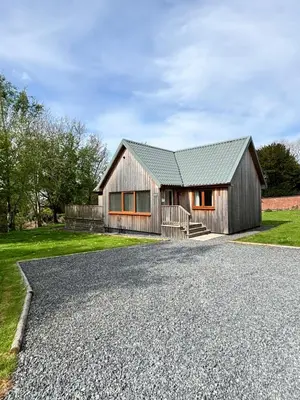 a house with a gravel driveway in front of it at Kestrel Lodge 2 with Hot Tub in Newton Stewart