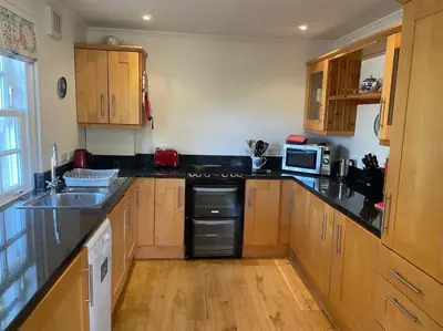 a kitchen with wooden cabinets and black counter tops at Private detached cottage sleeps 4 in Crieff