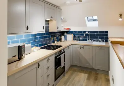a kitchen with white cabinets and blue tiles at Stroan in New Galloway