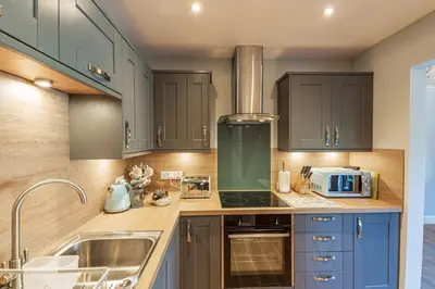 a kitchen with blue cabinets and a sink at Osprey Lodge 1 with Hot Tub in Newton Stewart