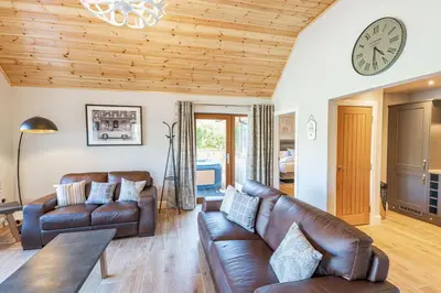 a living room with leather furniture and a clock at Osprey Lodge 1 with Hot Tub in Newton Stewart