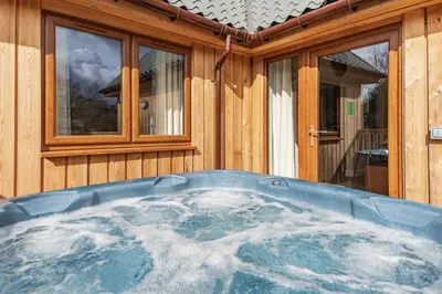 a hot tub in front of a wooden house at Osprey Lodge 1 with Hot Tub in Newton Stewart