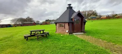 a small house and a bench in a field at Just Resort No29 in Balminnoch